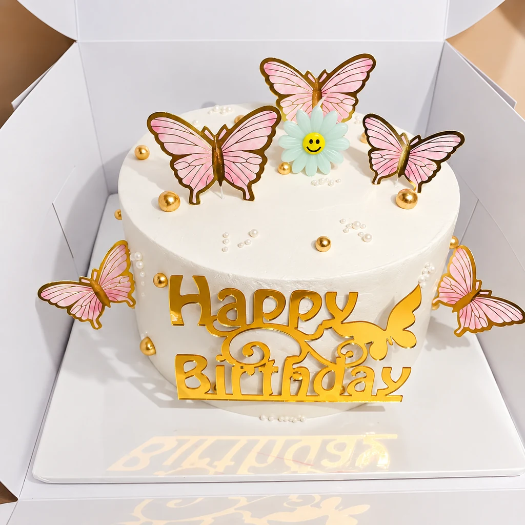 White birthday cake with pink butterflies, gold pearls and gold Happy Birthday topper