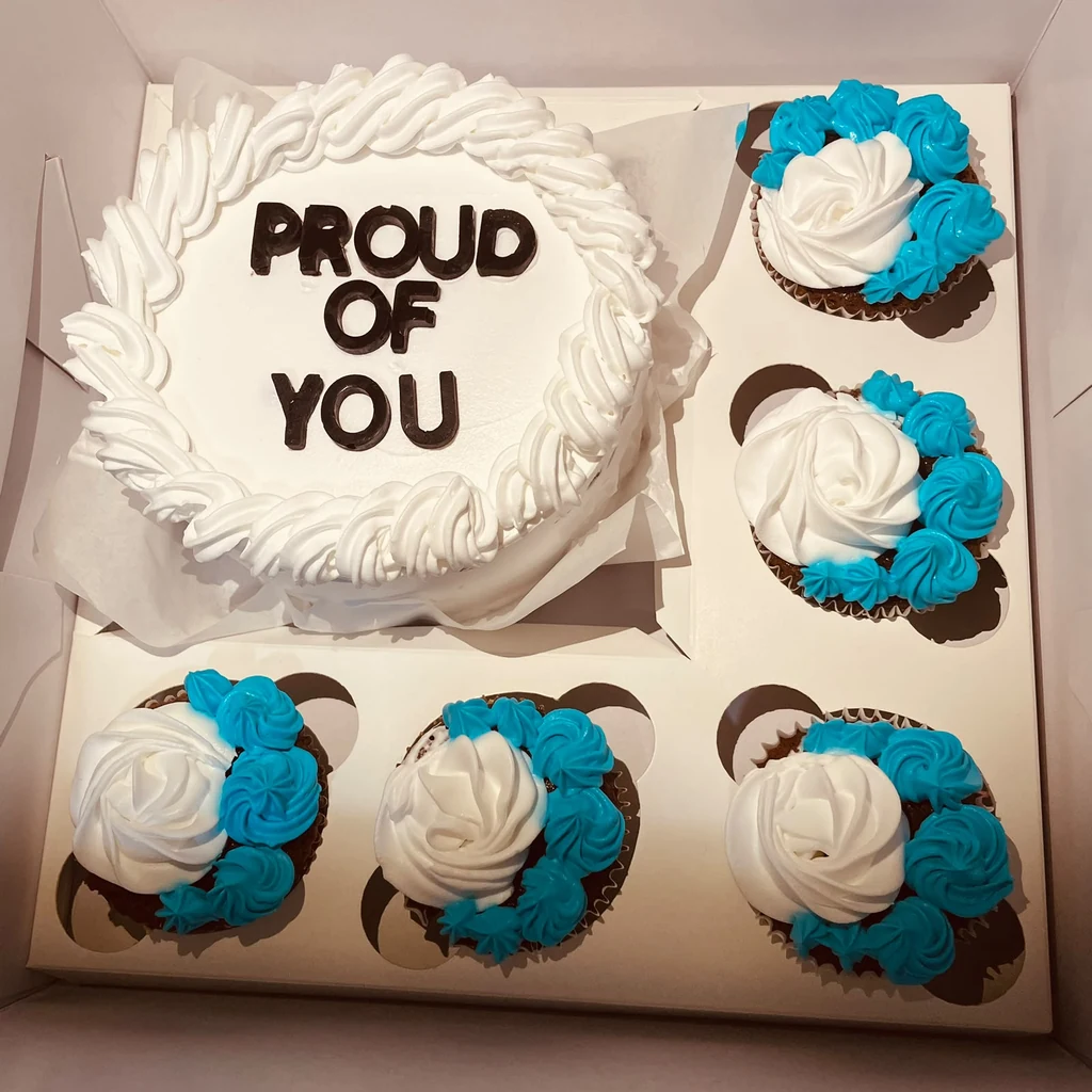 White Proud of You cake with five blue and white buttercream cupcakes