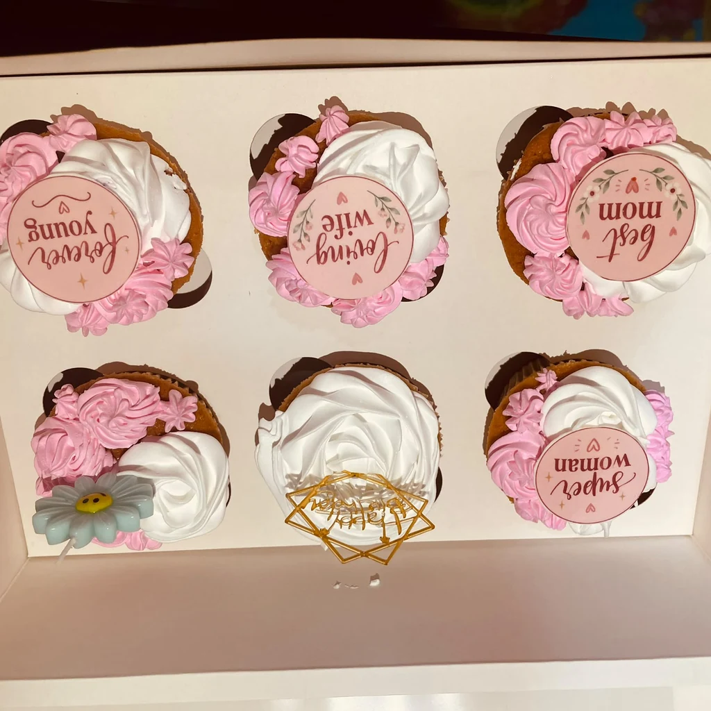 Six pink and white cupcakes with Forever Young, Loving Wife, Best Mom and Super Woman toppers