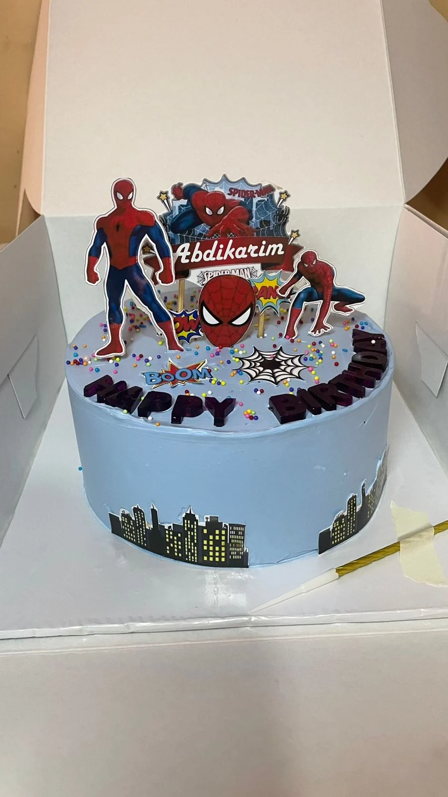 Light blue superhero cake with web decoration and character toppers by Moh Bakes & Treats
