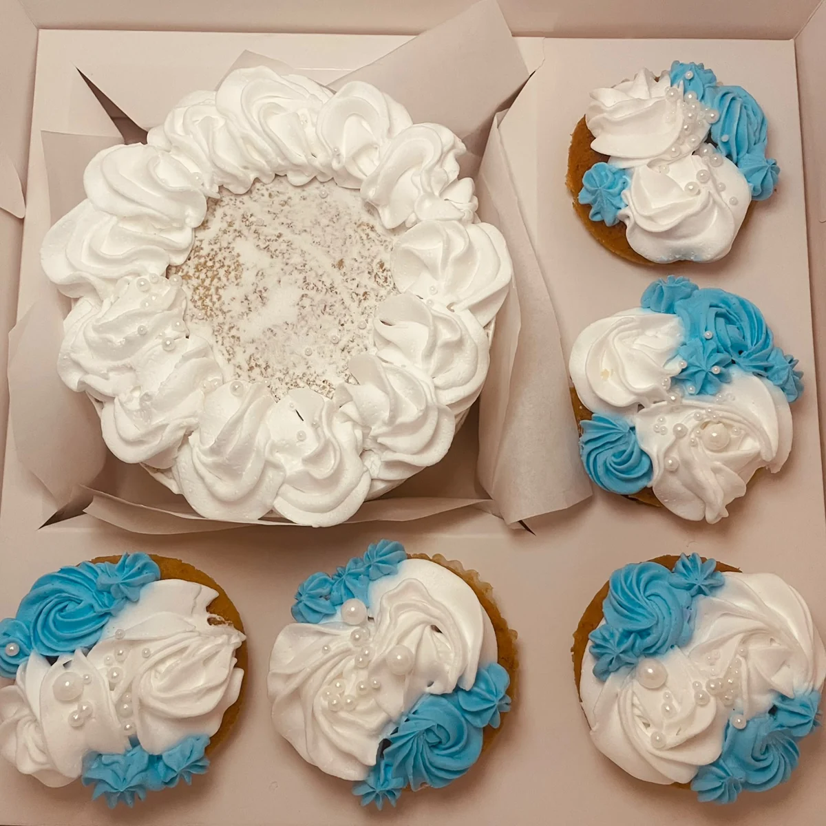 Piped cake and five decorated cupcakes in a presentation box by Moh Bakes & Treats