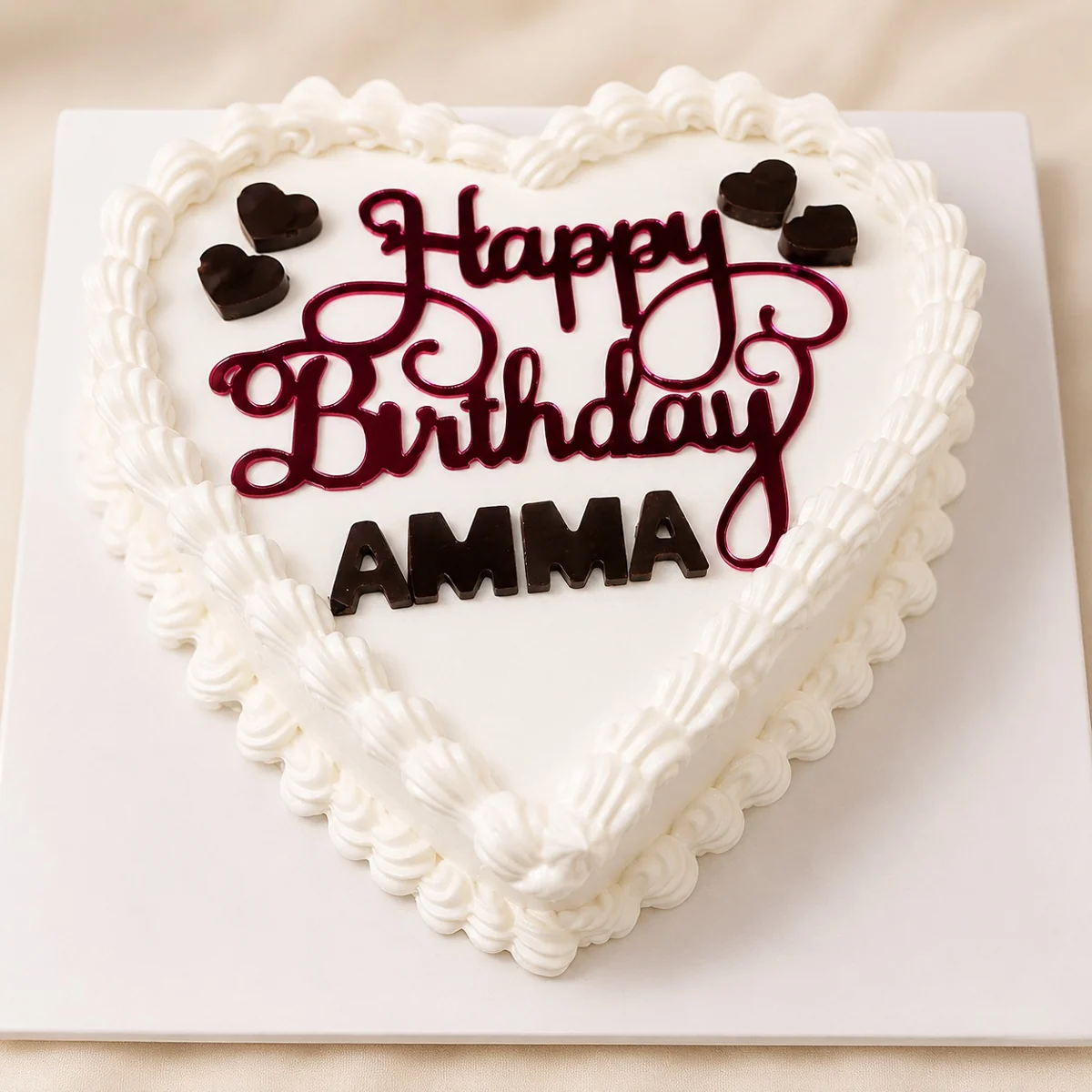 Heart-shaped cake with piped white borders and dark birthday lettering by Moh Bakes & Treats